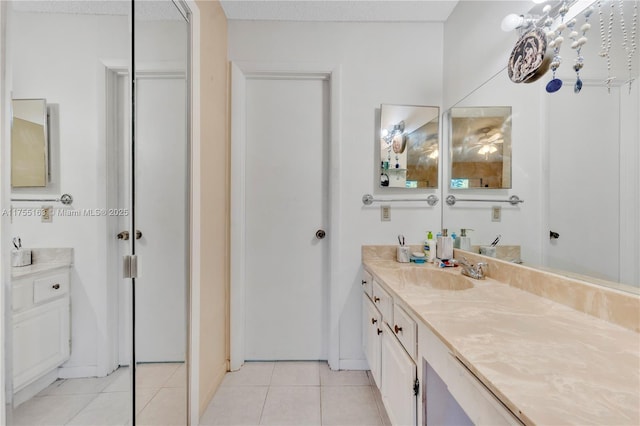 bathroom with a textured ceiling, tile patterned flooring, vanity, and baseboards