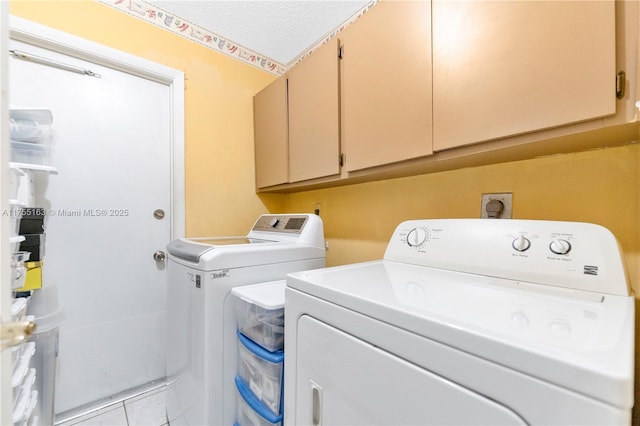 clothes washing area with cabinet space, a textured ceiling, washing machine and clothes dryer, and tile patterned floors