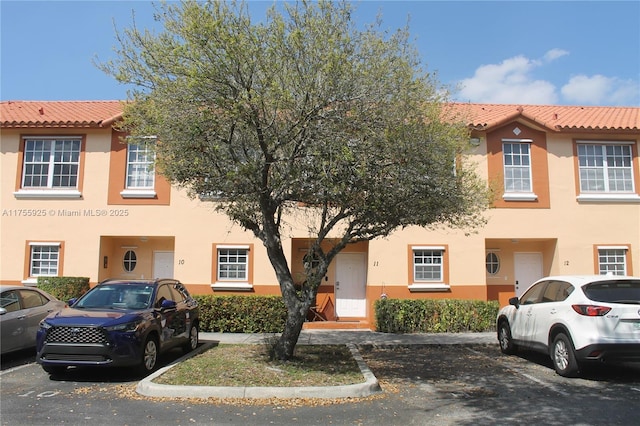 view of front of home featuring a tile roof, uncovered parking, and stucco siding