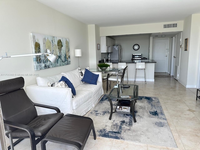 living room with visible vents, baseboards, and light tile patterned floors