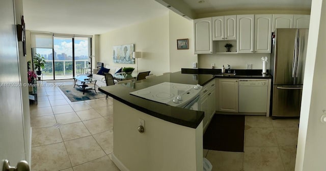 kitchen featuring light tile patterned floors, white appliances, dark countertops, and floor to ceiling windows