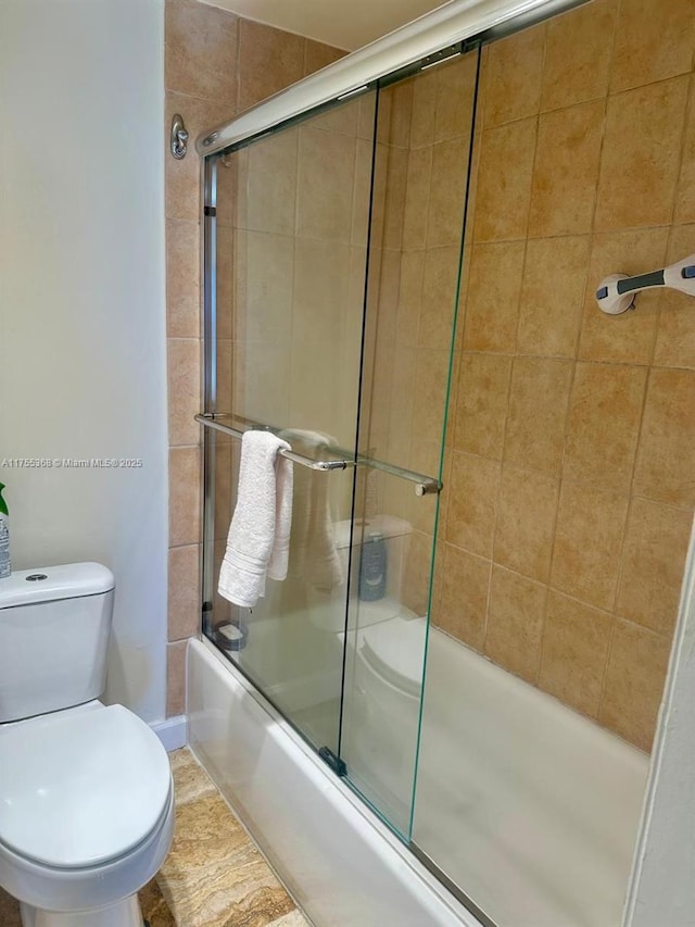 bathroom with bath / shower combo with glass door and toilet