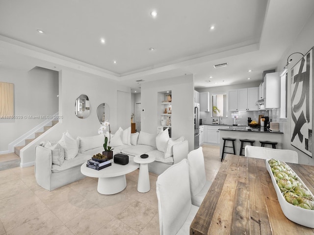 living room featuring visible vents, stairway, a raised ceiling, and recessed lighting