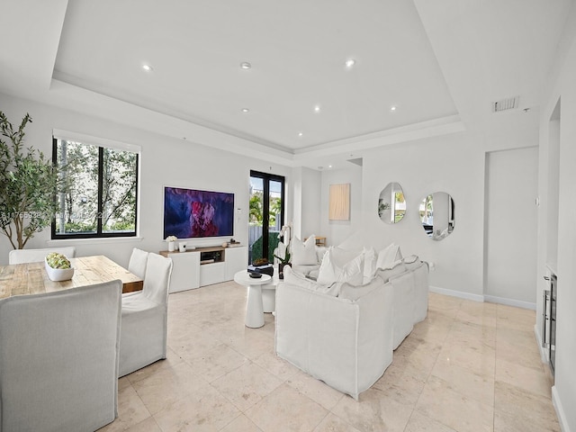 living area with baseboards, visible vents, a raised ceiling, and recessed lighting