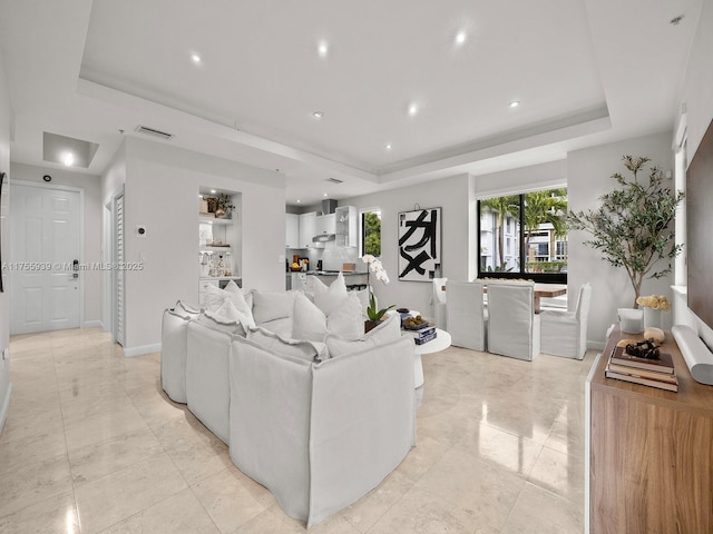 living area with plenty of natural light, visible vents, and a raised ceiling