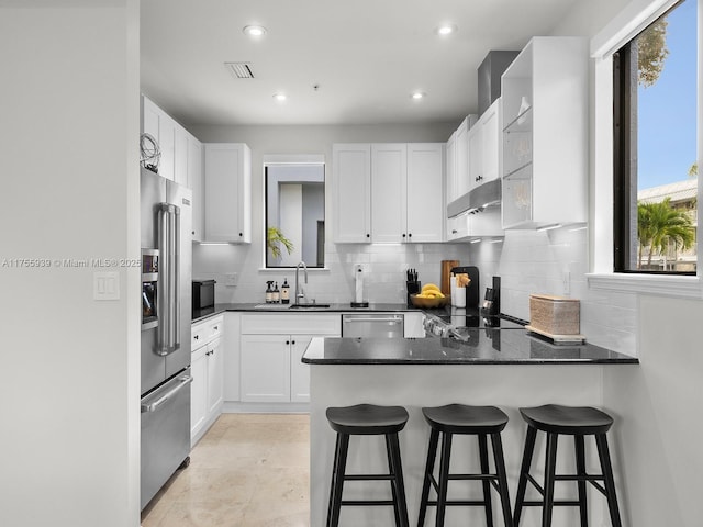 kitchen with backsplash, appliances with stainless steel finishes, a sink, a peninsula, and extractor fan