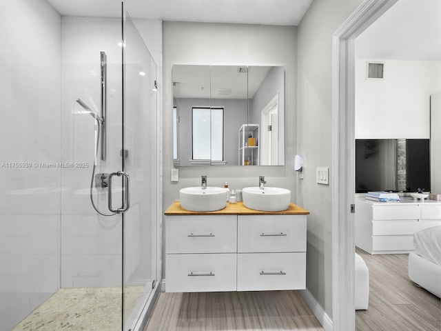 full bathroom with a stall shower, visible vents, a sink, and wood finished floors