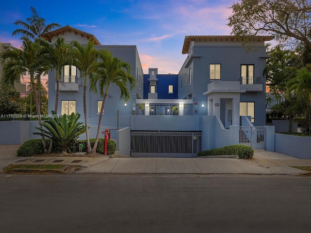 view of front of house featuring a balcony, a fenced front yard, a gate, and stucco siding