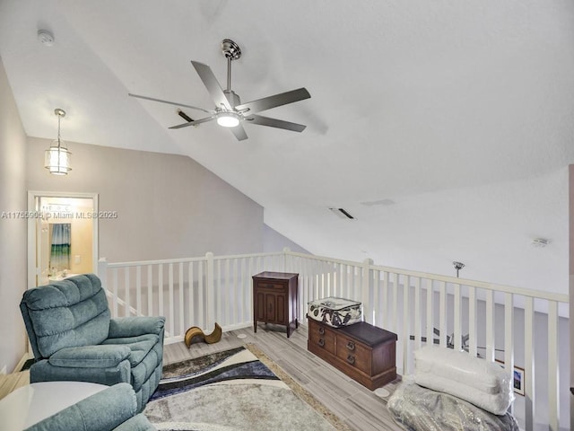 living area featuring light wood-style floors, lofted ceiling, visible vents, and a ceiling fan