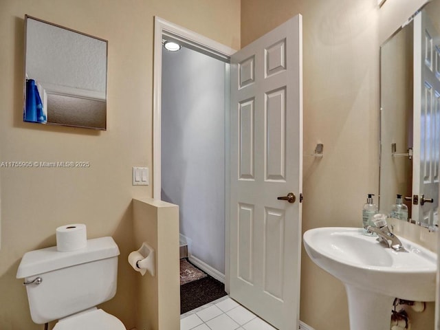 bathroom featuring a sink, tile patterned flooring, and toilet