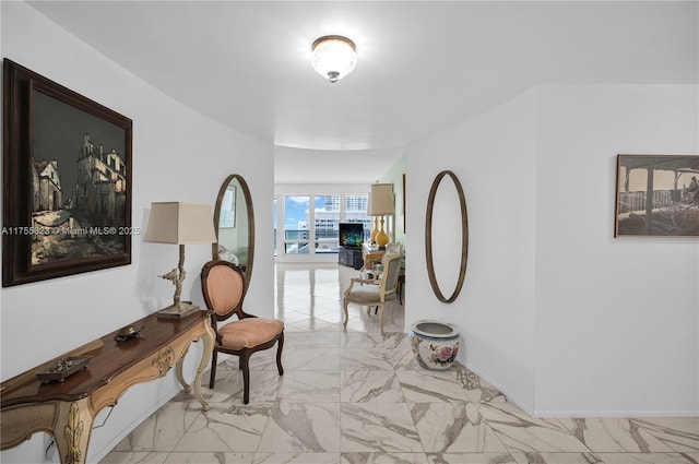 corridor featuring marble finish floor and baseboards