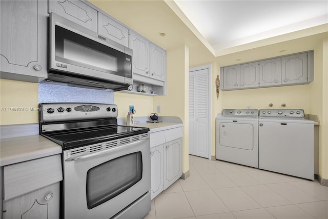 kitchen with stainless steel appliances, light countertops, washing machine and clothes dryer, and light tile patterned floors