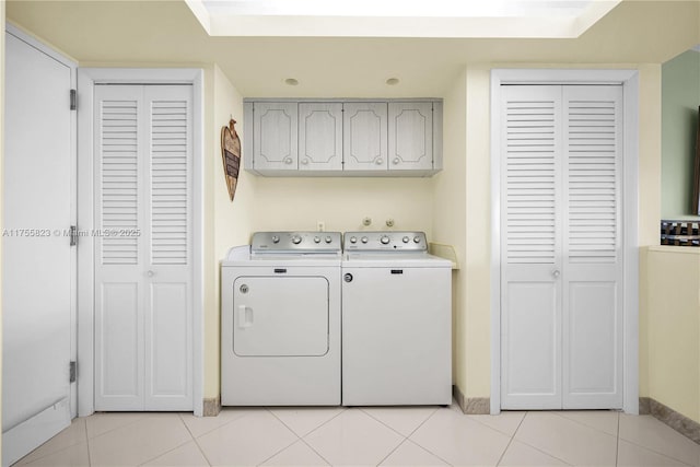 washroom featuring light tile patterned floors, separate washer and dryer, cabinet space, and baseboards