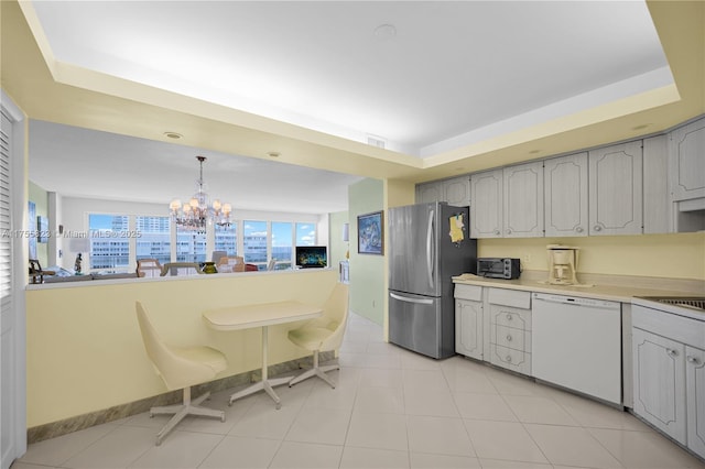 kitchen featuring visible vents, freestanding refrigerator, white dishwasher, light countertops, and a notable chandelier