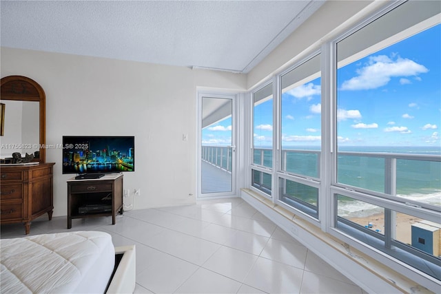 living area featuring a textured ceiling, a water view, and light tile patterned flooring