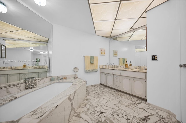 full bathroom featuring marble finish floor, a paneled ceiling, a garden tub, and vanity