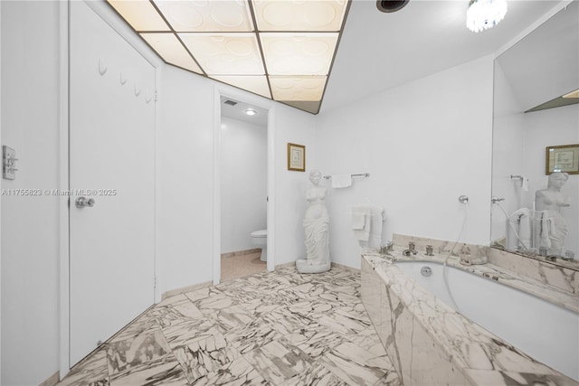 full bath featuring marble finish floor, a garden tub, and toilet