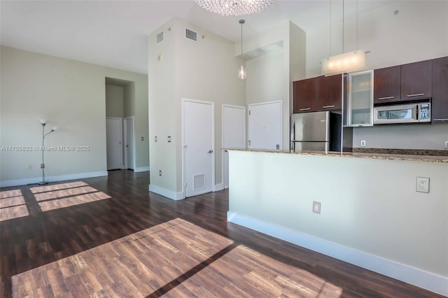 kitchen featuring dark brown cabinetry, visible vents, dark wood finished floors, a high ceiling, and stainless steel appliances