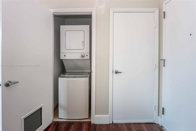 laundry room with dark wood-style floors, laundry area, stacked washer / dryer, and visible vents