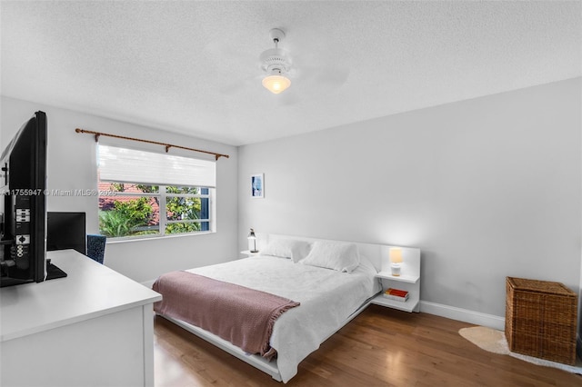 bedroom with a textured ceiling, wood finished floors, a ceiling fan, and baseboards