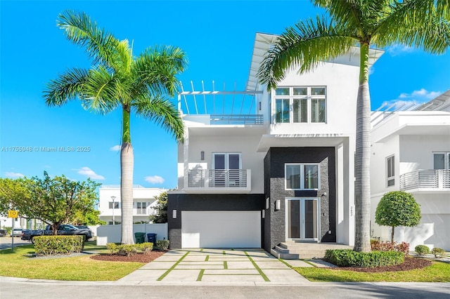 view of front facade featuring driveway, a balcony, an attached garage, and stucco siding