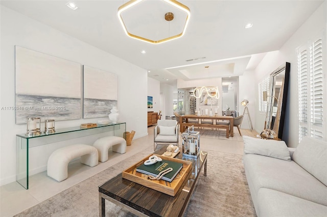 living room with baseboards, a raised ceiling, and recessed lighting