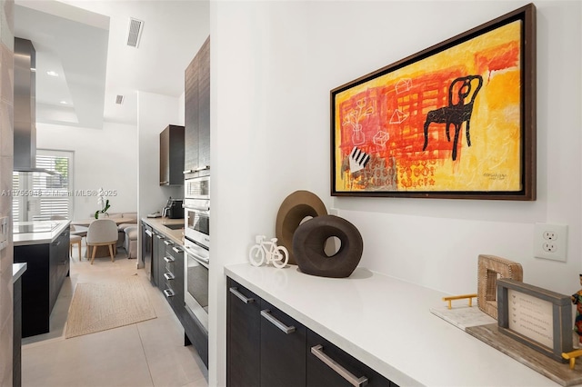 kitchen with light countertops, dark cabinetry, modern cabinets, and stainless steel oven