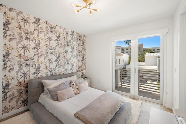 bedroom with access to exterior, a notable chandelier, wood finished floors, baseboards, and wallpapered walls