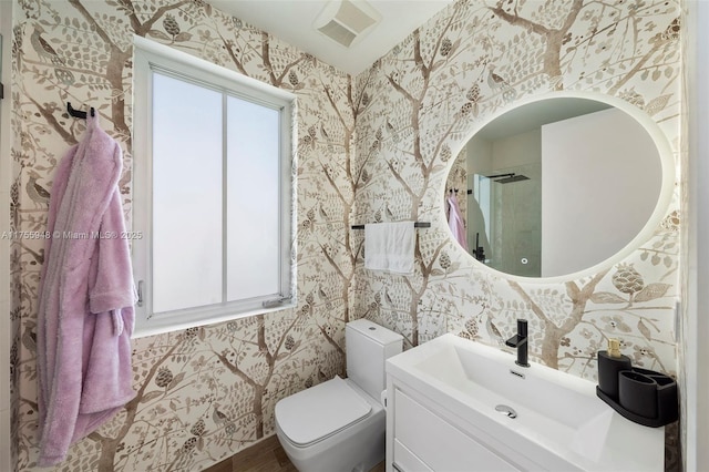 full bath with toilet, vanity, visible vents, and wallpapered walls