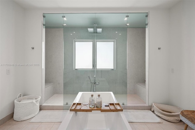 full bath featuring baseboards, tile patterned flooring, a freestanding tub, and a shower stall