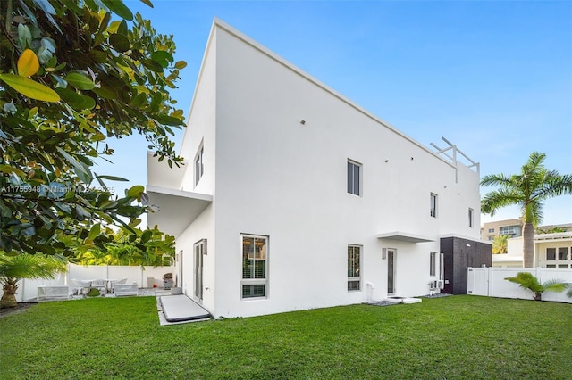 rear view of property with a yard, a patio area, a fenced backyard, and stucco siding