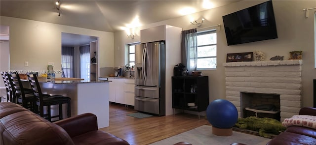 living area featuring vaulted ceiling, a fireplace, and wood finished floors