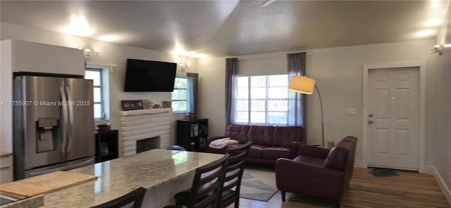 kitchen featuring a healthy amount of sunlight, a fireplace, a breakfast bar, and stainless steel fridge with ice dispenser