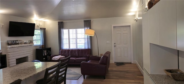 living area featuring a brick fireplace and wood finished floors