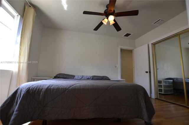 bedroom featuring a ceiling fan, a closet, visible vents, and wood finished floors