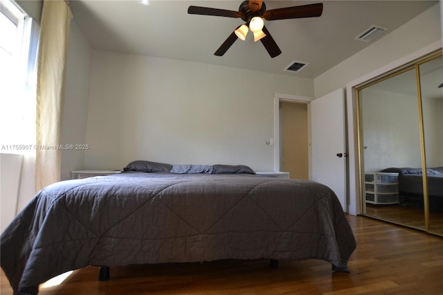 bedroom featuring a closet, wood finished floors, visible vents, and a ceiling fan