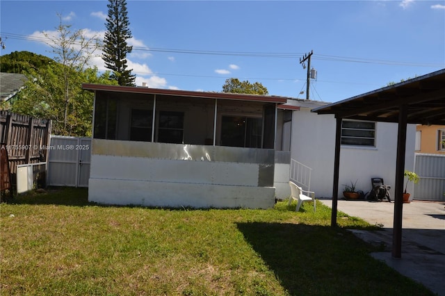 back of house featuring a lawn, fence, and a sunroom