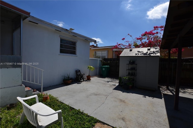 view of patio / terrace with an outdoor structure, fence, and a storage unit