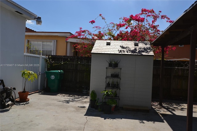 view of patio / terrace with an outbuilding, fence, and a storage shed