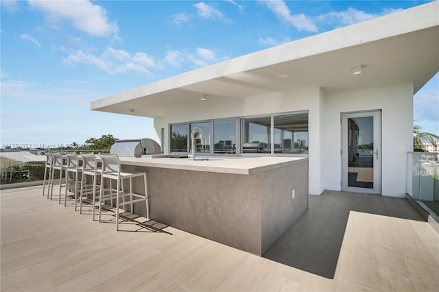 view of patio / terrace featuring outdoor wet bar, a sink, and exterior kitchen
