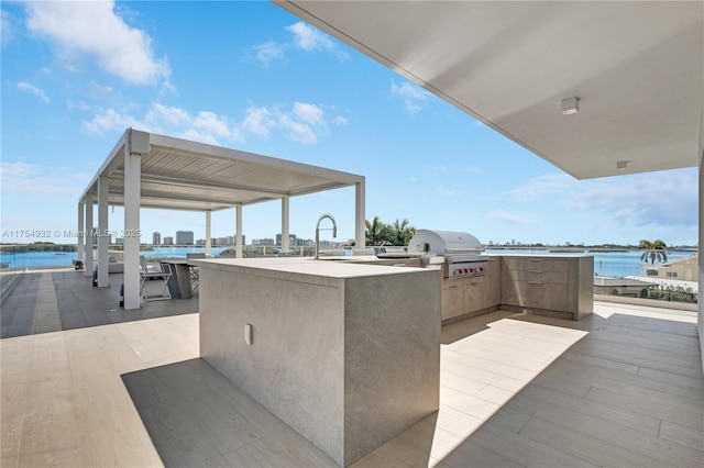 view of patio / terrace featuring a sink, an outdoor kitchen, a grill, and a water view