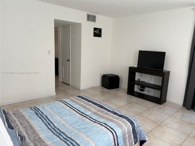 bedroom with visible vents, a textured ceiling, and baseboards