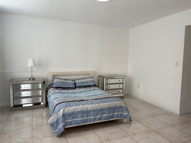 bedroom with marble finish floor, a textured ceiling, and baseboards