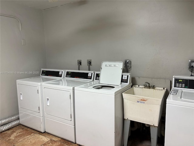 common laundry area with stone finish flooring, washer and clothes dryer, and a sink