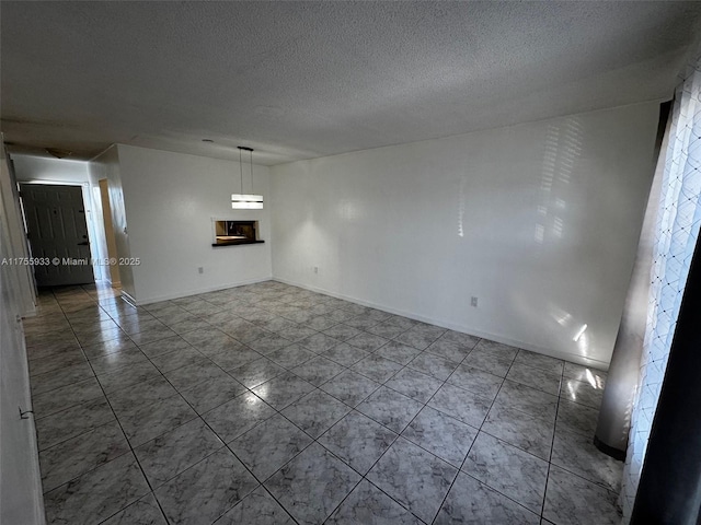 tiled spare room with baseboards and a textured ceiling