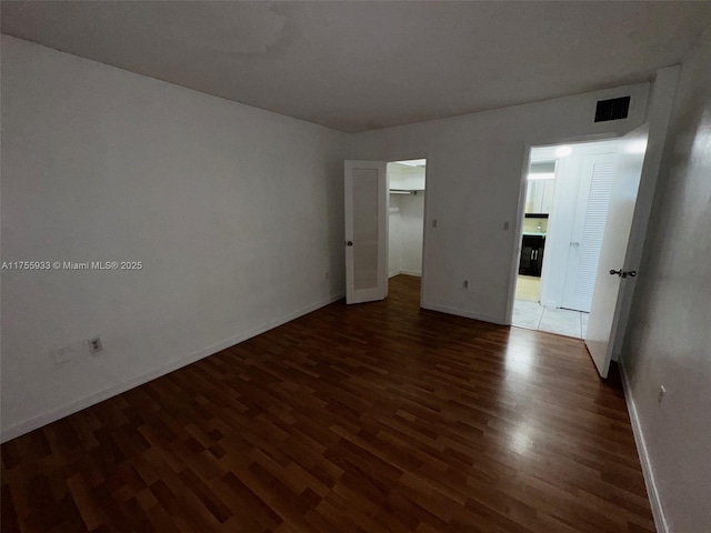 spare room featuring baseboards, visible vents, and dark wood finished floors