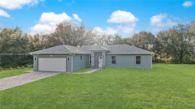 single story home with a front lawn, decorative driveway, a shingled roof, and an attached garage