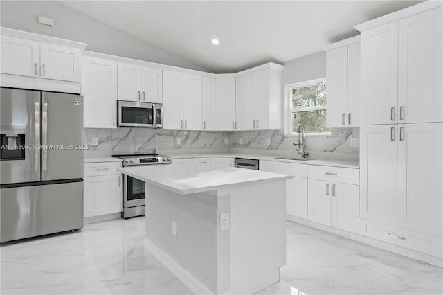 kitchen featuring marble finish floor, vaulted ceiling, stainless steel appliances, light countertops, and a sink