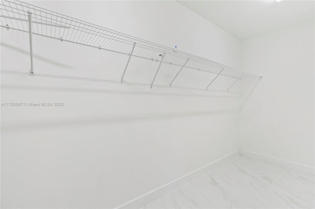 walk in closet featuring marble finish floor