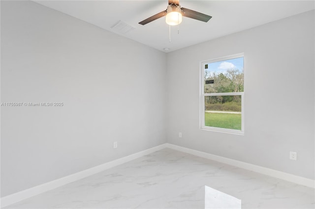 spare room with marble finish floor, visible vents, baseboards, and a ceiling fan